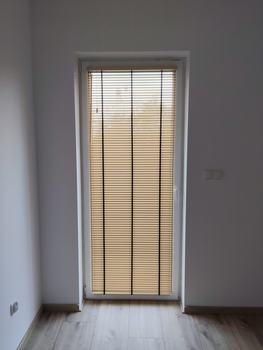 Po montażu, żaluzje drewniane 25 mm z drabinką taśmową: drzwi na taras w salonie