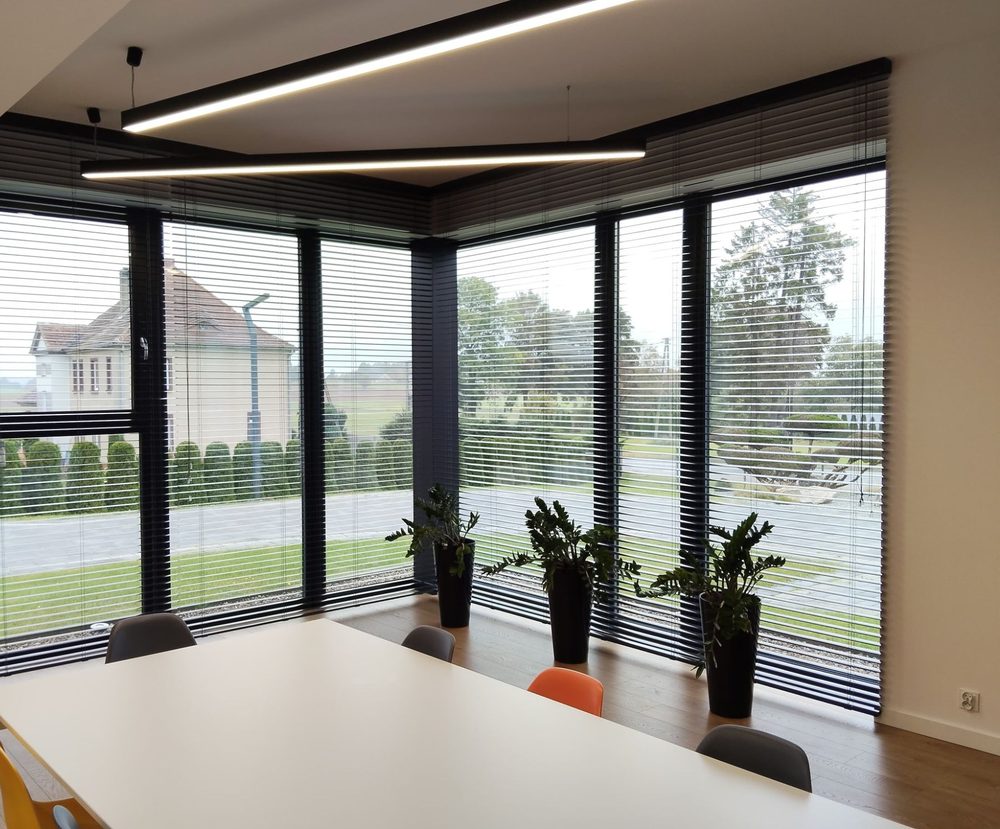 Żaluzje aluminiowe 50 mm w narożnym przeszkleniu biura, lamele otwarte